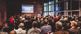 Fototapeta Nowy Jork - Business and entrepreneurship symposium. Speaker giving a talk at business meeting. Audience in conference hall. Rear view of unrecognized participant in audience.