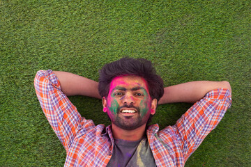 A YOUNG MAN POSING ON GRASS AFTER PLAYING HOLI	