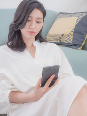 Wall Mural - Young asian woman using smartphone at home