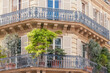 Beautiful Haussmannian building facade in Paris with balcony decorated with plants