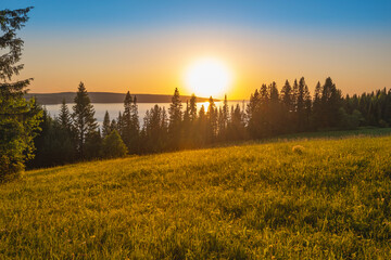Wall Mural - panoramic view of the kama river from the hill, green meadow, rural road, sunset sky and sun rays.