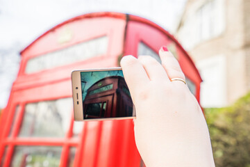 Wall Mural - LONDON, UK - 17 FEBRUARY, 2017: An old traditional English phone box. Woman taking a photo.