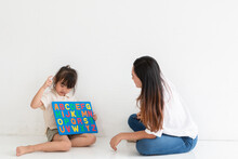 Young Little Girl Playing In The Alphabet Toy With Her Mother, She Is Learning English Alphabet. Young Mother Teaching Her Daughter Girl English Alphabet For Learning Spelling.