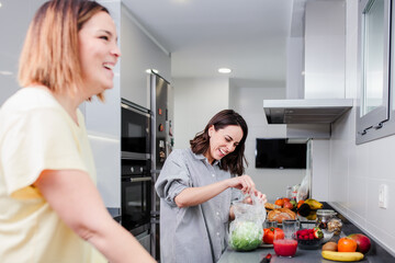 Wall Mural - Women preparing healthy food playing with vegetables in kitchen having fun concept dieting nutrition.