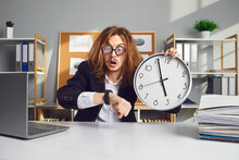 Employee Working Under Pressure. Funny Stressed Young Office Worker With Messy Long Hair Holding Clock, Looking At Wristwatch And Panicking Over Missed Deadline Or Being Terribly Late For Work Meeting