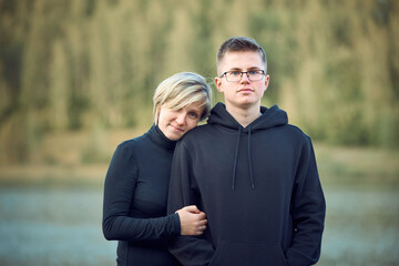 Mother and adult son on the background of the lake and forest in a blur. The concept of family values.