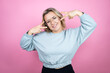 © Irene - Young caucasian woman wearing sweatshirt over pink background Doing peace symbol with fingers over face, smiling cheerful showing victory