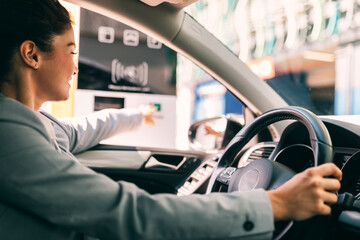 Woman is driving into a parking garage and is collecting ticket from car park machine.