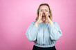 © Irene - Young caucasian woman wearing sweatshirt over pink background shouting and screaming loud to side with hands on mouth