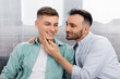 homosexual man touching face of cheerful husband at home