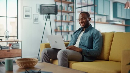 Aufkleber - Handsome Black African American Man Having a Video Call on Laptop Computer while Sitting on a Sofa in Living Room