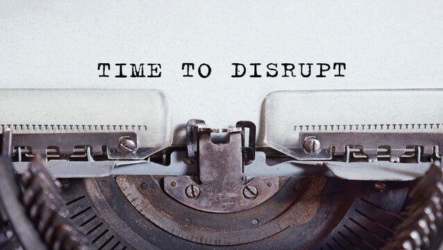 The text TIME TO DISRUPT is typed on paper by an antique typewriter. Vintage inscription, retro style, grunge, concept.