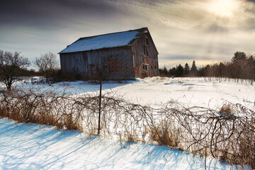 Wall Mural - Rural winter scenes of large open fields and sky with barns, farmland and the setting sun.  Ice and cascades.  