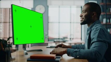 Wall Mural - Handsome Black African American Specialist Working on Desktop Computer with Green Screen Mock Up Display at Home Living Room. Freelance Man Chatting to Clients Over the Internet on Social Networks.