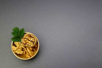 Wall Mural - Peeled walnuts in a round wooden bowl on a gray background.