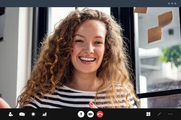 Happy pretty Caucasian woman smiling at the camera while making video call at home