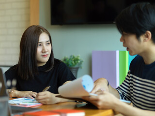 Wall Mural - Two office worker discussing on their work with paperwork on clipboard