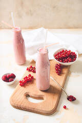 Wall Mural - Bottles of tasty smoothie with cranberry and raspberry on light background