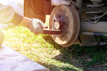 Canvas Print - men's gloved hands repair of car drum brake himself. disassembles a jammed disk with a hammer. repair of broken car drum brake disassembled outdoor. flare