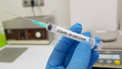 Wall Mural - Selective focus closeup of a hand with a glove holding an investigated coronavirus vaccine