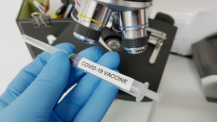 Wall Mural - Selective focus closeup of a hand with a glove holding an investigated coronavirus vaccine