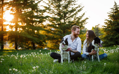 Wall Mural - Happy young couple walking, playing with dogs in a park