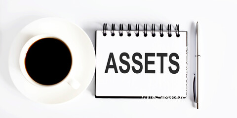 Poster - ASSETS , planning concept. Spiral notebook with text on white background with coffee