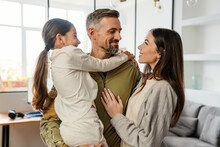 Happy Masculine Military Man Smiling And Hugging His Family Indoors