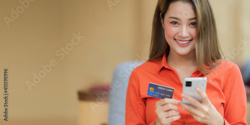 Portrait of Happy woman holding smart phone with credit card and smiling face in creative office © Naypong Studio