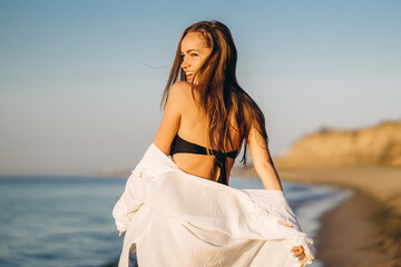 Wall Mural - Pretty brunette woman relaxing on the beach at the sea.