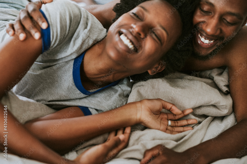 Cute happy black couple playing in bed - obrazy, fototapety, plakaty 