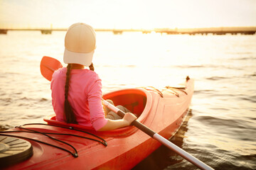 Poster - Little girl kayaking on river, back view. Summer camp activity