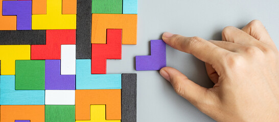 hand connecting geometric shape block with colorful wood puzzle pieces. logical thinking, business logic, Conundrum, decision, solutions, rational, mission, success, goals and strategy concepts