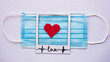 medical blue mask with red heart in the middle with word love  on picture frame on white background