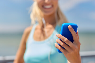 Poster - sport, fitness and technology concept - close up of happy smiling sporty young woman with smartphone and earphones