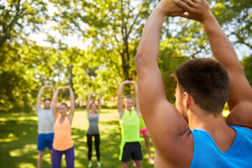 Canvas Print - fitness, sport and healthy lifestyle concept - group of happy people exercising with trainer at summer park