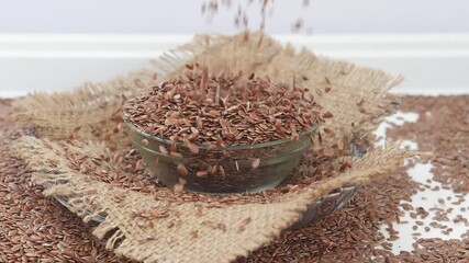 Sticker - Close shot of dropping flax seeds over a bowl filled with flax seeds