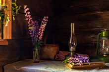 Still Life Of Vintage Items And A Bouquet Of Lupins On A Table By The Window In An Old Village House.