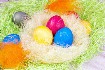 Colorful painted Easter eggs decorations in the nest on light green background.