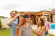© Impact Photography - Man placing blindfold over woman's eyes while playing blind man's buff