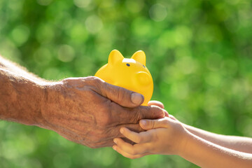 Family holding piggy bank in hands against green spring background