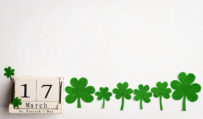 Wall Mural - Happy St. Patrick's Day concept, wooden calendar with green paper clover leaf on white wooden background. Flat lay, top view with copy space.