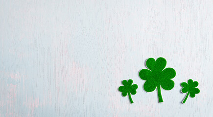 Wall Mural - Happy St. Patrick's Day concept, Green paper clover leaf on pastel wooden background. Flat lay, top view with copy space.