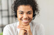 © Vadim Pastuh - Headshot of friendly African American millennial woman in a headset sitting with her hands on a chin, working in the customer service department as call center operator, helping client with inquiry
