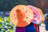 Fototapeta Bambus - Chinese Women in Native Dress Hold an umbrella standing beside lotus lake