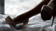foot fetish, female legs with sexual and erotic high heels shoes on white bed, closeup view of feet