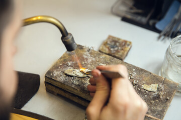 Wall Mural - Heating. Close up hands of jeweller, goldsmiths making of golden ring with gemstone using professional tools. Craft production, precious and luxury jewel, hand made occupation. Workshop, artwork.