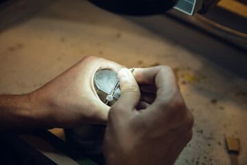 Wall Mural - Leveling. Close up hands of jeweller, goldsmiths making of golden ring with gemstone using professional tools. Craft production, precious and luxury jewel, hand made occupation. Workshop, artwork.