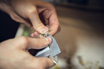 Wall Mural - Craftsman. Close up hands of jeweller, goldsmiths making of silver ring with gemstone using professional tools. Craft production, precious and luxury jewel, hand made occupation. Workshop, artwork.