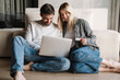 © Drobot Dean - Happy young couple using credit card and laptop while sitting on floor